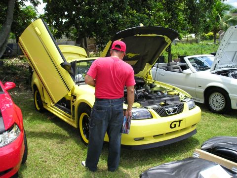 2009 Ford Mustang - A yellow convertible Mustang with custom doors is displayed with its hood open, alongside another convertible.