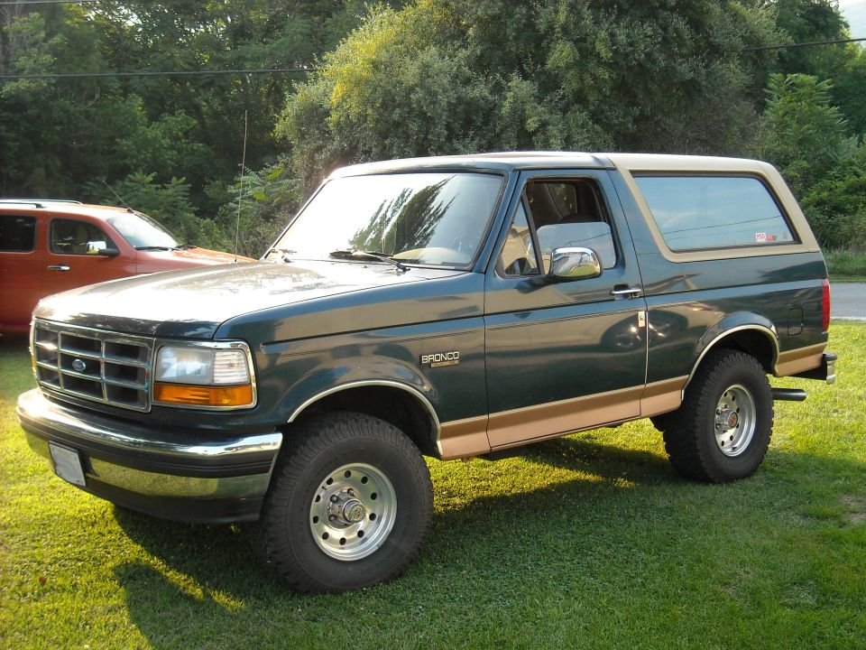 Green and tan two-tone Ford Bronco SUV parked on grass, front three-quarter view