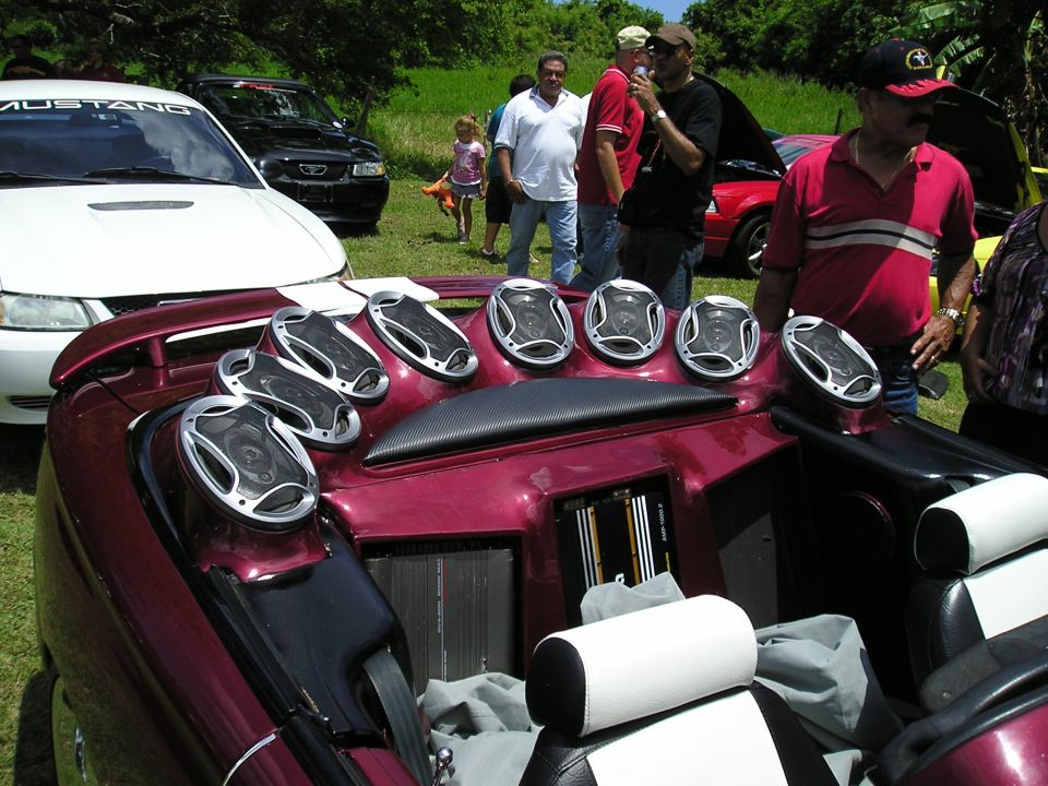 Maroon customized car interior with eight speakers and two amplifiers visible