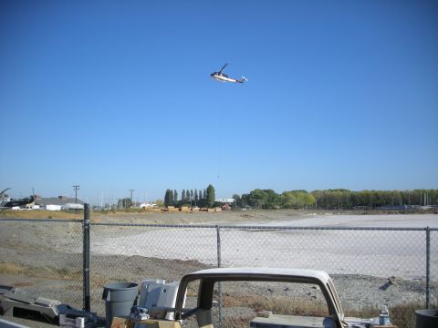 1991 Ford Bronco - A helicopter is seen in the sky, suspended by a cable, over a construction area.