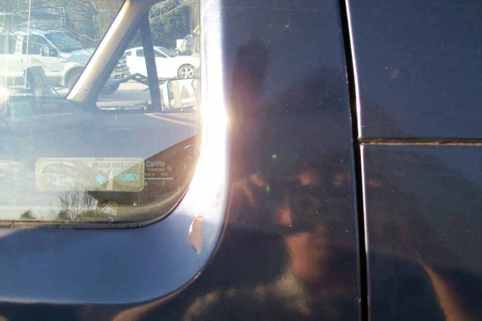 Close-up of dark blue truck A-pillar and windshield corner with Ford Carlite glass etching