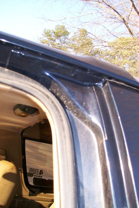 1988 Ford Bronco - Detail of the interior door frame and window seal, with a reflection of the outdoors visible in the glass.