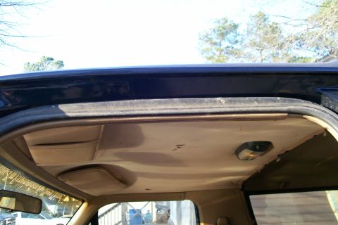 1988 Ford Bronco - Close-up of the interior headliner and door frame of a vehicle, with visible storage pockets.