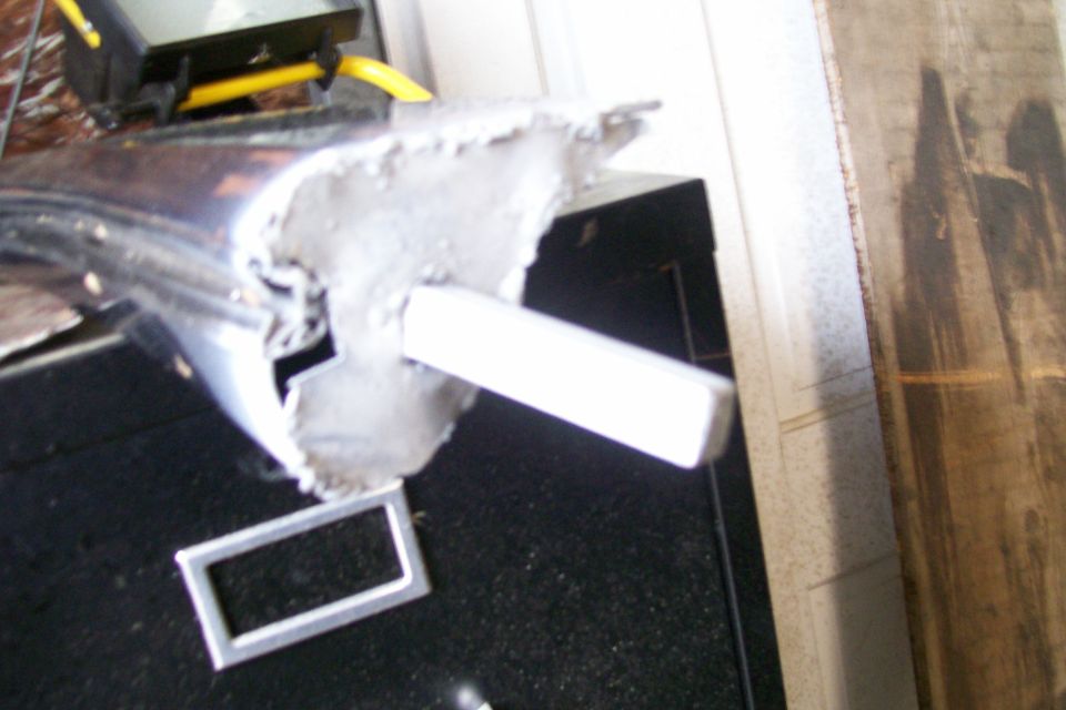 Cut metal body section with welds resting on a workshop floor
