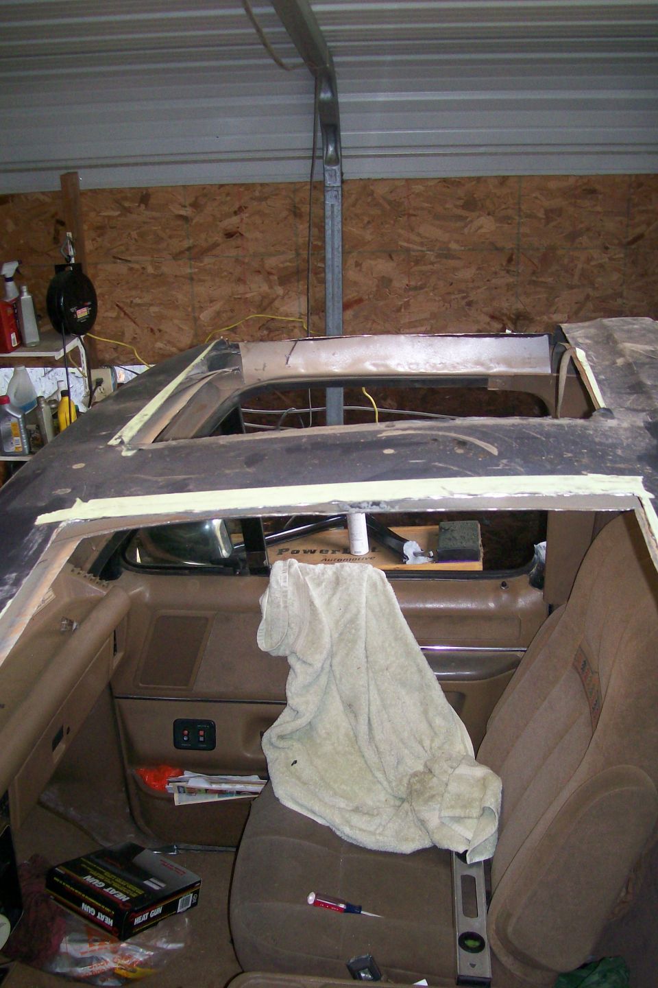 Truck cab roof cut open during bodywork in a shop, tan interior exposed with tools on the seat