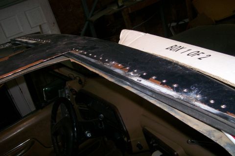 1988 Ford Bronco - Roof panel of a vehicle stripped to bare metal showing welded roof bows and seam; cardboard box labeled 'Body 1 of 2' rests on the roof.