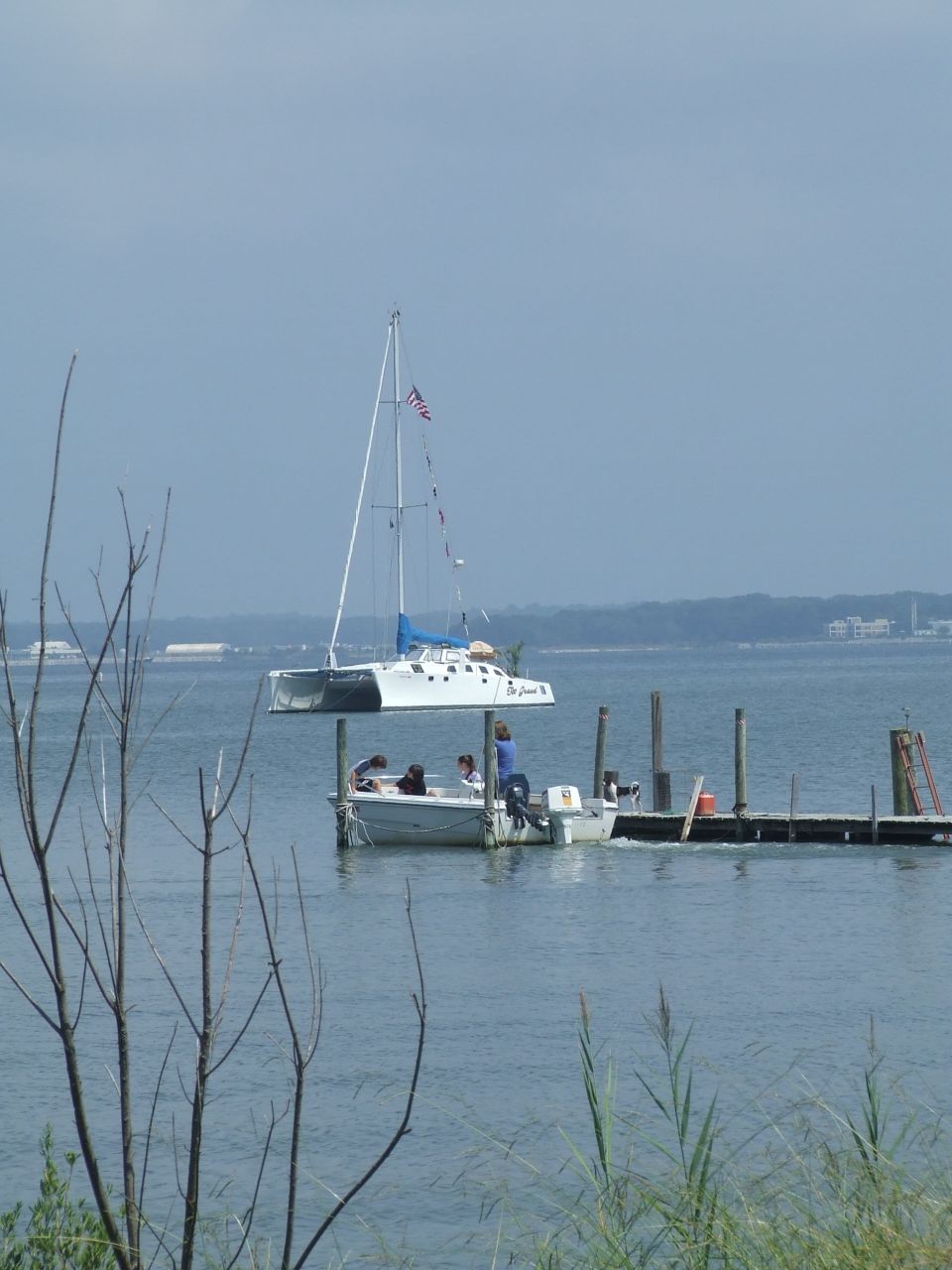 White catamaran sailboat docked at a pier with people on board.