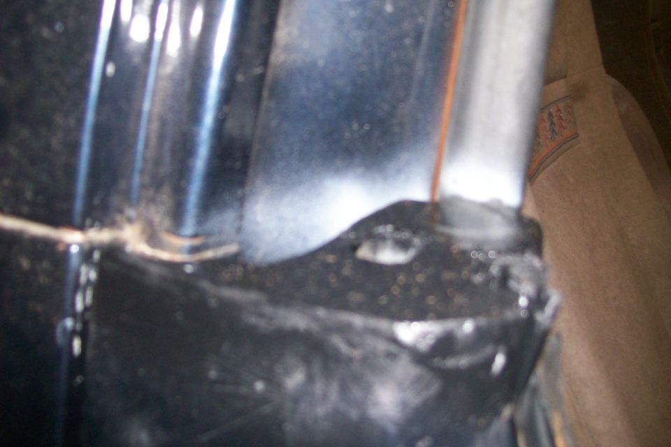 Close-up of a dark vehicle part with debris, next to tan patterned fabric.