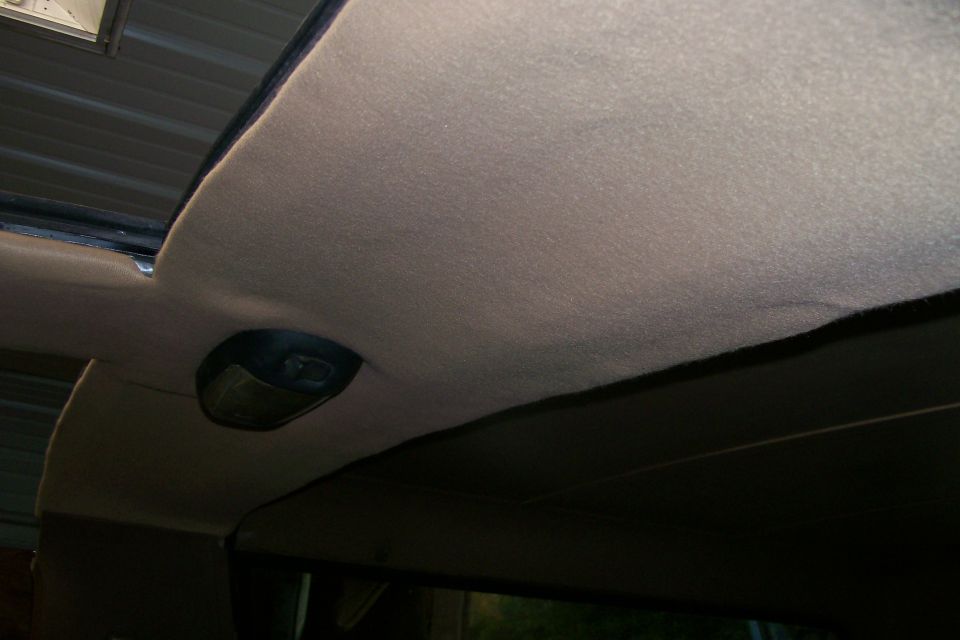 Tan cloth headliner inside a truck cab with black dome light housing