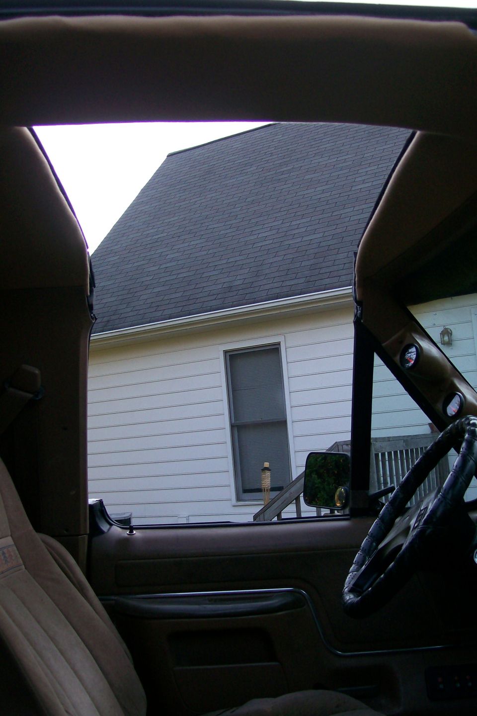 Tan interior of an 80s Ford truck with A-pillar gauge pods and leather wheel