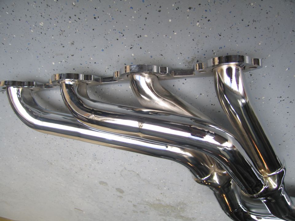 Chrome exhaust headers on a speckled gray floor