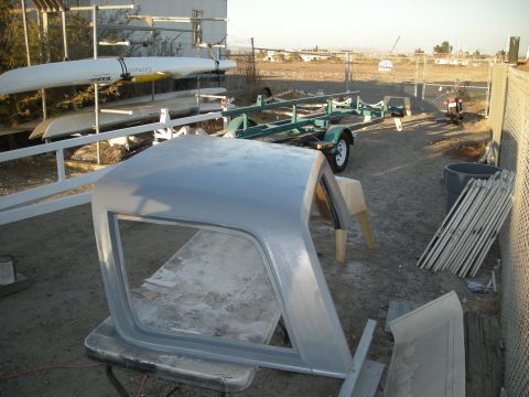 1991 Ford Bronco - A disassembled Ford Bronco hardtop sits on a table, with a boat trailer and kayaks visible in the yard.