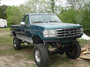 1996 Ford F-150 - A green pickup truck is parked outdoors with a lifted suspension and large off-road tires.