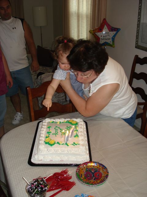 2000 Ford Crown Victoria - A woman helps a toddler blow out candles on a birthday cake that reads "Lucy" and "40".