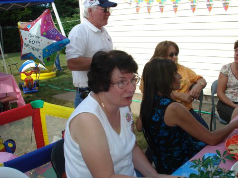 2000 Ford Crown Victoria - A group of people celebrate a 60th birthday outdoors with decorations and a bounce house.
