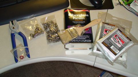 1979 Ford Bronco - A collection of items for fiberglass repair, including resin, cloth, a brush, fasteners, and a pair of pliers.