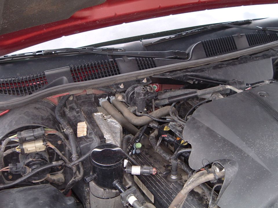 Engine bay of red car showing black engine cover, hoses and wiring harness connectors