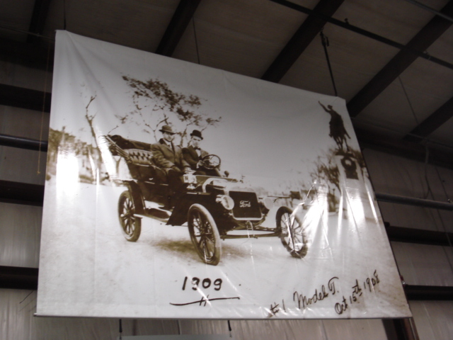 Sepia-toned photograph of a 1909 Ford Model T with two men, viewed from the front-right