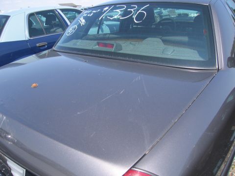 2001 Ford Crown Victoria - The rear of a gray 2001 Ford Crown Victoria is shown, with a handwritten number on the rear window and another vehicle visible behind it.