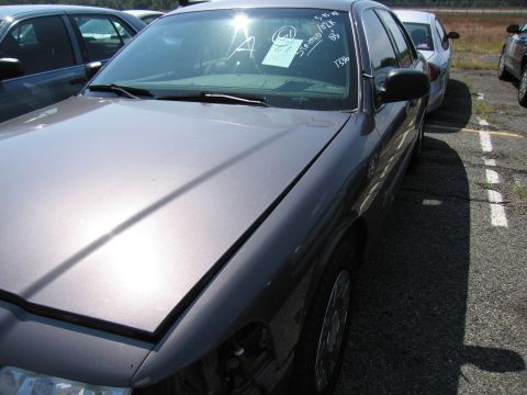 2001 Ford Crown Victoria - A gray 2001 Ford Crown Victoria is parked in an outdoor lot, with other vehicles visible in the background.