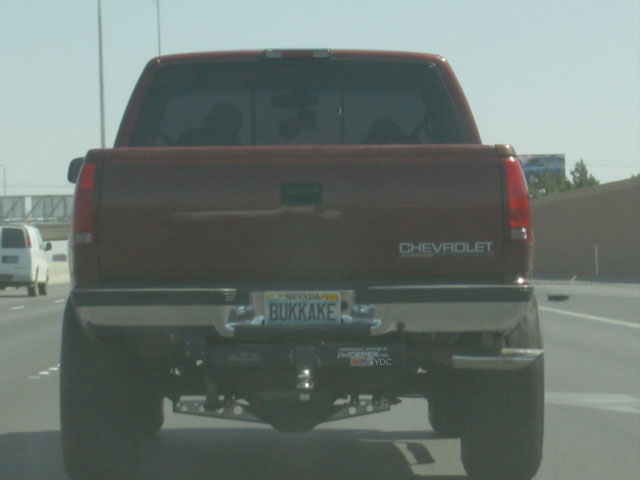 Rear of maroon lifted Chevrolet pickup with Nevada plate reading BUKKAKE on highway