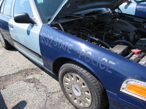 2001 Ford Crown Victoria - A police car with its hood open, showing the engine compartment and "1832 STATE POLICE" text on the fender.