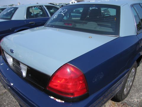 2001 Ford Crown Victoria - Two Ford Crown Victorias parked outdoors, one with white markings on its rear window.
