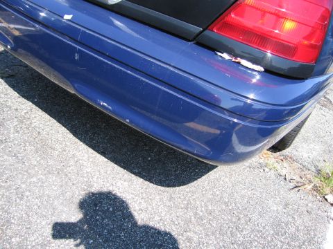 2001 Ford Crown Victoria - Close-up of the rear corner of a blue sedan, showing damage to the bumper and taillight.
