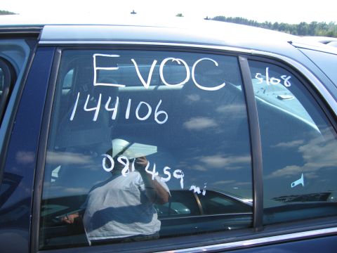 2001 Ford Crown Victoria - White writing on the rear passenger door of a blue sedan indicates 'EVOC 144106 5108 081459 mi'.