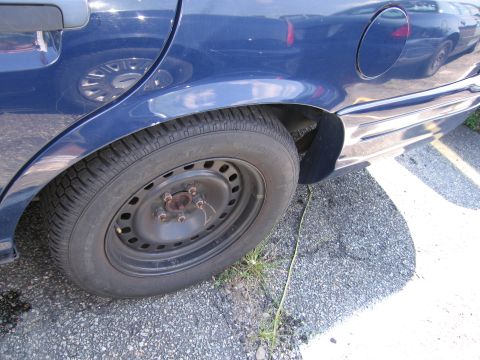 2001 Ford Crown Victoria - Close-up of the rear wheel well and side panel of a blue sedan.