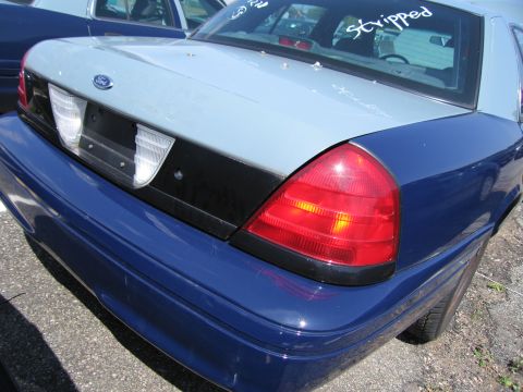 2001 Ford Crown Victoria - The rear of a two-tone Ford Crown Victoria, possibly a 2001 model, is visible with text on the rear window.
