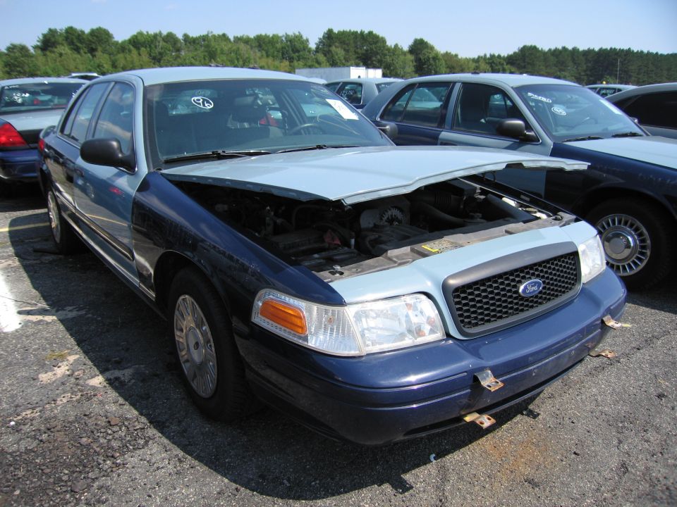 2001 Ford Crown Victoria with hood open, showing engine. Two-tone blue and light blue paint. Front end is dark blue