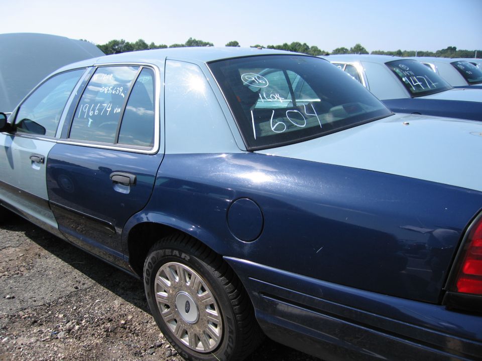 Two-tone blue Ford Crown Victoria in a lot, hood up. Numbers written on windows