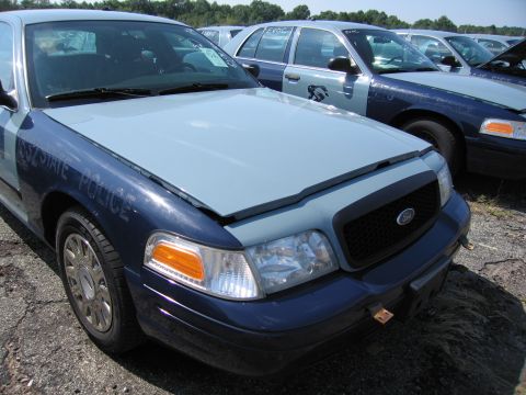 2001 Ford Crown Victoria - A line of police cars, including a Ford Crown Victoria, are parked in an outdoor lot.