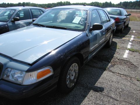 2001 Ford Crown Victoria - A fleet of Ford Crown Victorias are parked in an outdoor lot, with one in the foreground showing a two-tone paint scheme.