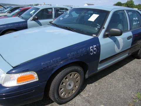 2001 Ford Crown Victoria - A fleet of police cars are parked in a lot. The closest vehicle is a dark blue and light blue Ford Crown Victoria with 'STATE POLICE 553' m…
