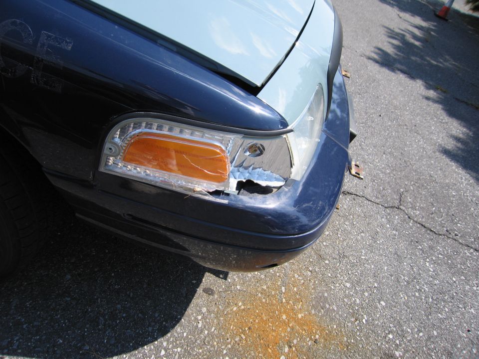 Dark blue and light blue 2001 Ford Crown Victoria front fender with cracked headlight and broken grille