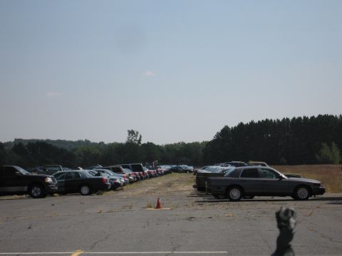 2001 Ford Crown Victoria - A dark 2001 Ford Crown Victoria sedan is parked in a lot with other vehicles under a clear sky.