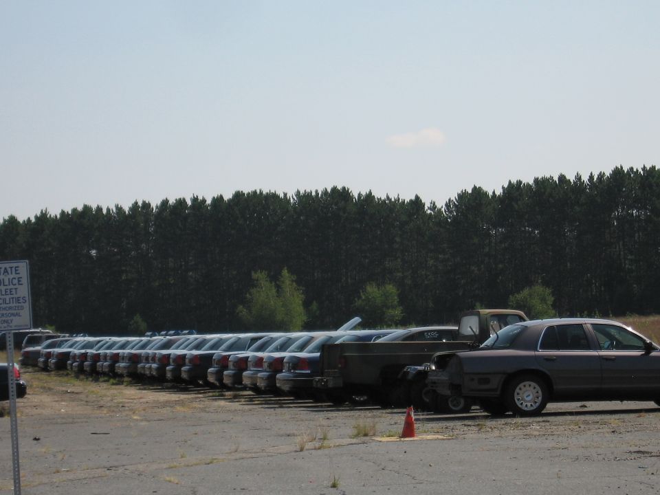 Side view of a line of 2001 Ford Crown Victoria police cars parked in a lot