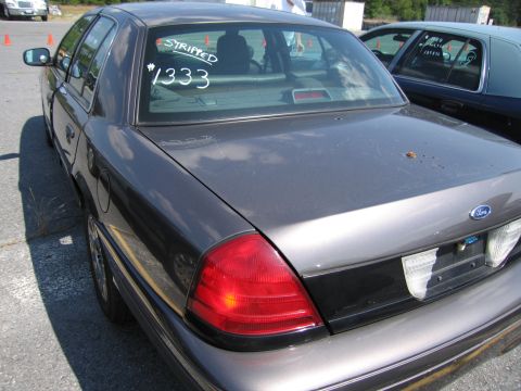 2001 Ford Crown Victoria - Gray 2001 Ford Crown Victoria with custom markings on the rear window, parked next to another Crown Victoria.