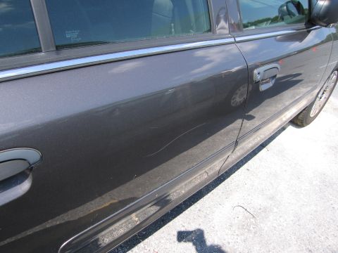 2001 Ford Crown Victoria - Close-up of a car door showing damage and a reflection of a wheel.