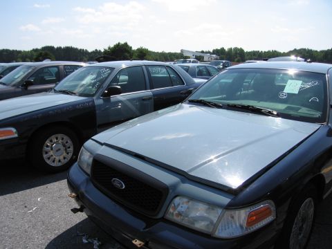 2001 Ford Crown Victoria - A light blue and dark blue Ford Crown Victoria is parked in a lot with other vehicles under a sunny sky.