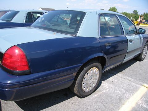 2001 Ford Crown Victoria - A two-tone Ford Crown Victoria is parked in a lot with another similar vehicle visible.