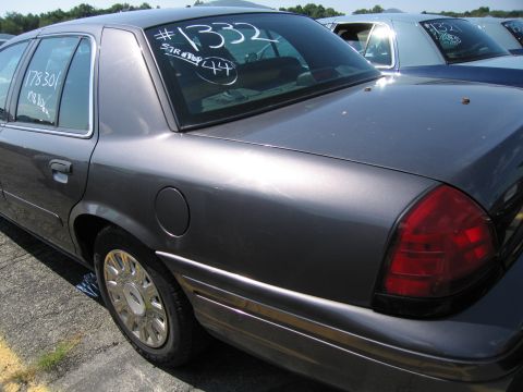 2001 Ford Crown Victoria - A dark gray sedan is parked in a lot, with white markings on its rear window.