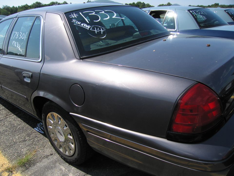 Rear quarter view of dark gray sedan with white markings on rear window