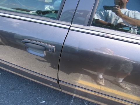 2001 Ford Crown Victoria - Close-up of a car's side door and handle, with reflections visible on the paint.