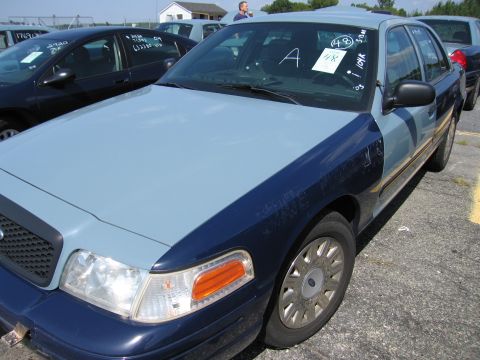 2001 Ford Crown Victoria - A two-tone Ford Crown Victoria is parked in a lot with other vehicles, some with handwritten notes on windshields.