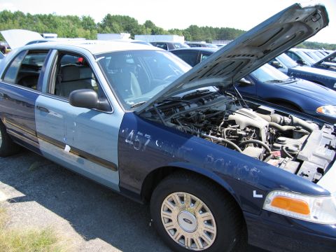 2001 Ford Crown Victoria - A two-tone 2001 Ford Crown Victoria is parked with its hood open, revealing the engine compartment. The vehicle has the number '457' marked…
