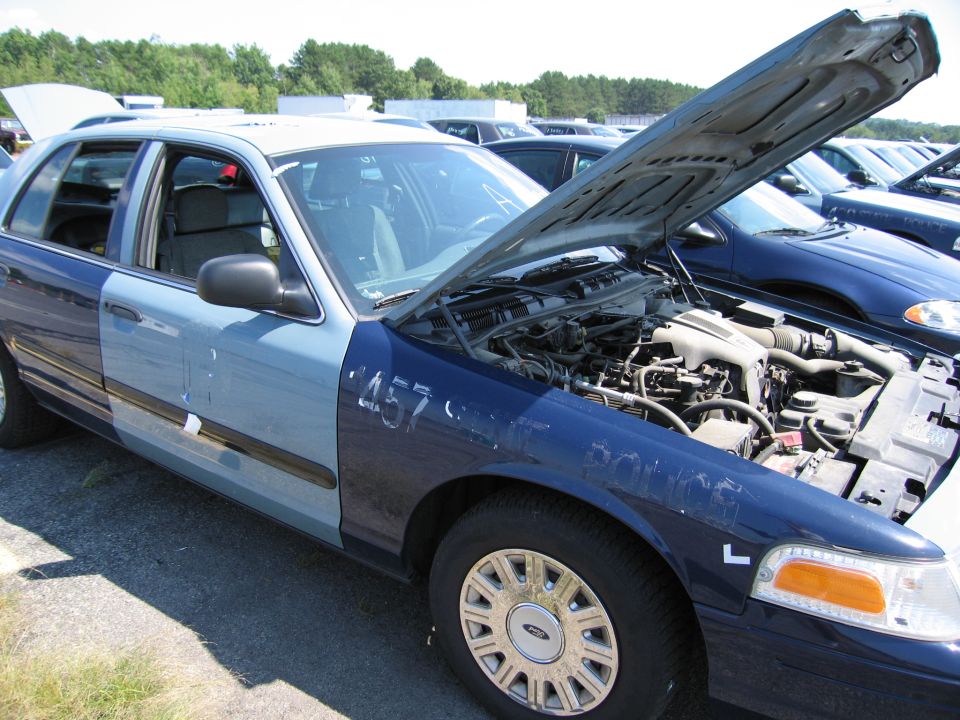 Blue and light blue 2001 Ford Crown Victoria with hood open, showing engine. Numbers '457' visible on fender