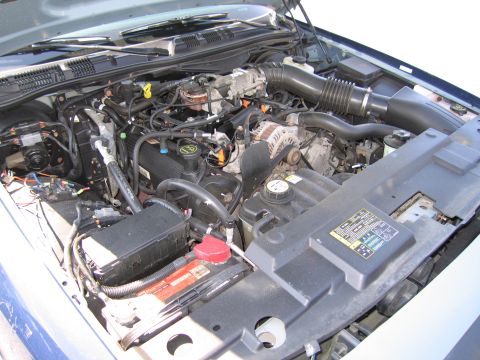 2001 Ford Crown Victoria - The engine bay of a 2001 Ford Crown Victoria is visible, the V8 engine, battery, and various engine components.